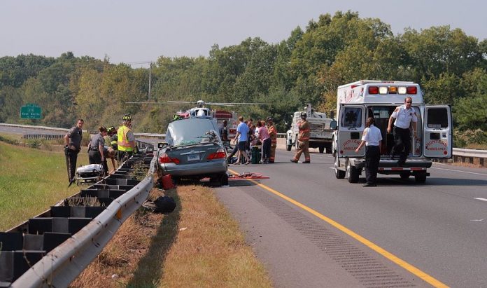 Car accident at side of road with emergency workers and ambulance; image by Ragesoss, via Wikimedia Commons, CC BY-SA 3.0, no changes.